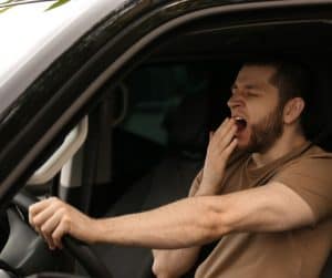 a man yawning while at the wheel