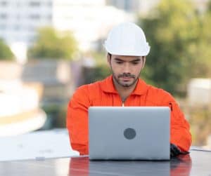 Construction worker using laptop computer outside.