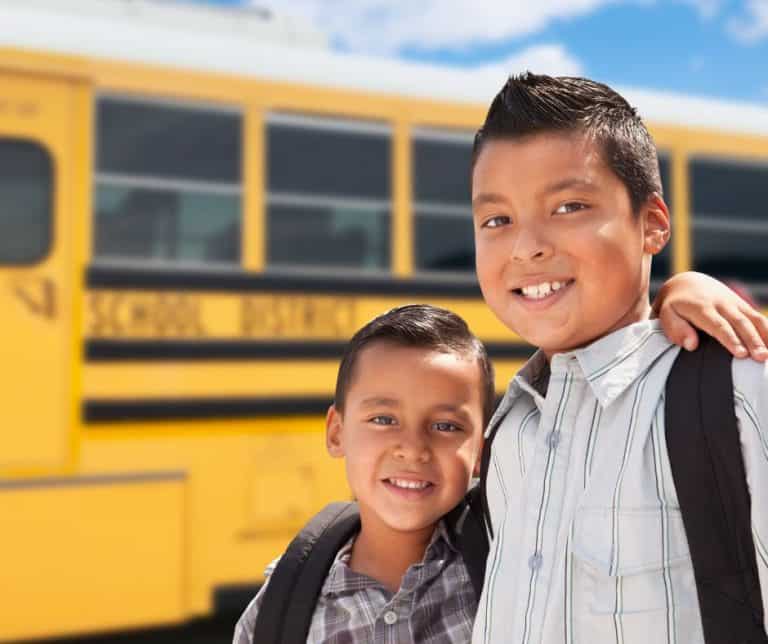 Two kids in front of a school bus